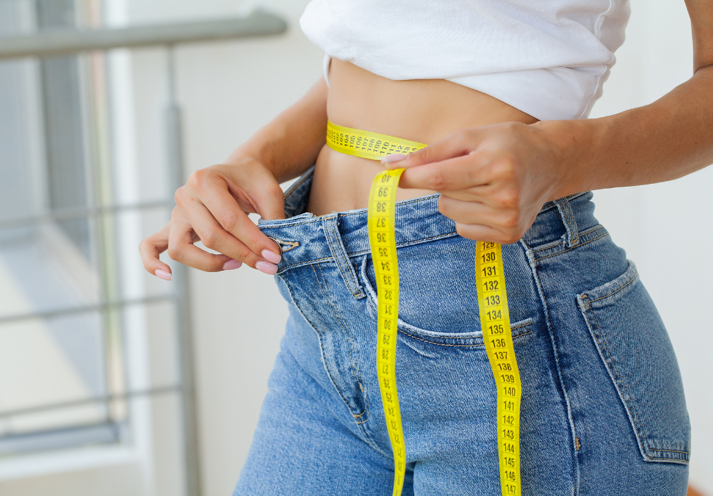 woman measuring waist in larger jeans